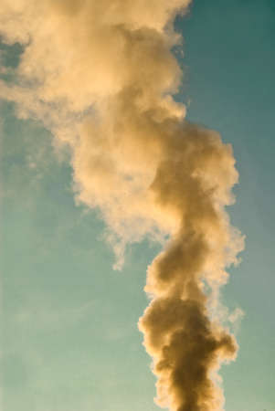 yellowish column of smoke in front of blue skyの写真素材