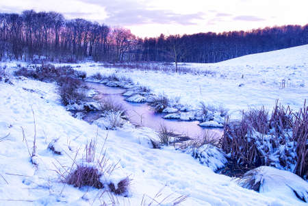 winterly natural landscape with small river at dawnの写真素材