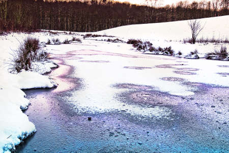 winterly natural landscape with small river at dawnの写真素材