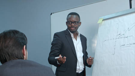 Afro-american businessman making presentation of a business plan on the flipchart