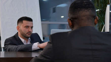 Two young businessmen discussing project at meeting