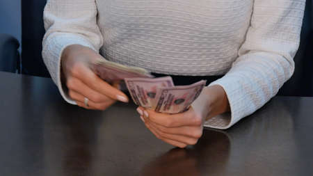Businesswoman counting dollar bank note at desk