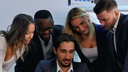 Modern young business people looking at smartphone screen, laughing and discussingの写真素材