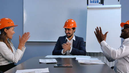 Successful in business multiracial team of engineers celebrating success shaking hands and smiling. Professional shot in 4K resolution. 085. You can use it e.g. in your commercial video, business, presentation, broadcast video.の写真素材