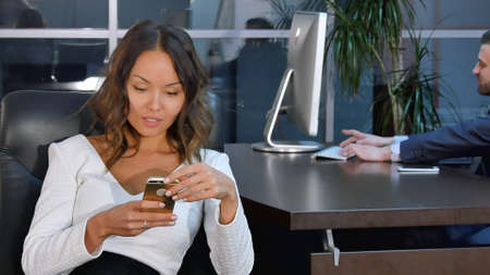 Young asian businesswoman using mobile phone in office. Professional shot in 4K resolution. 085. You can use it e.g. in your commercial video, business, presentation, broadcast video.の写真素材