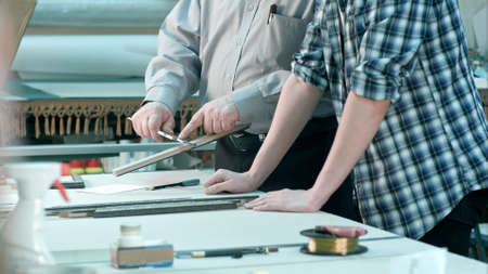 Male workers measuring size of frame behind the desk in workshop. Professional shot in 4K resolution. 083. You can use it e.g. in your commercial video, business, presentation, broadcast video.の写真素材