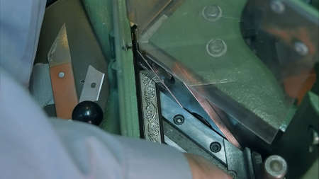 Professional framer hand holding frame, cutting it with machine. Close up. Slow motion. Professional...
