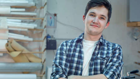 Cheerful young workre in a frame atelier workshop smiling and looking at camera. Close up. Professional shot in 4K resolution. 083. You can use it e.g. in your commercial video, business, presentation, broadcast video.の写真素材