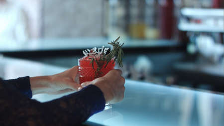 female hands holding red cocktail in the barの写真素材