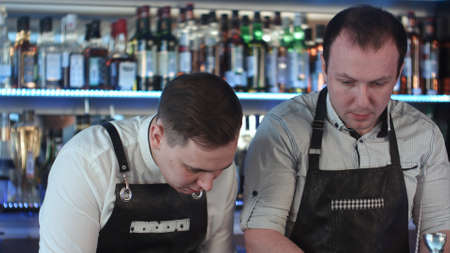 Two barmanan working and discussing something at counter in barの写真素材