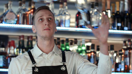 Young professional barman in action with shaker and bottle making cocktail drinksの写真素材