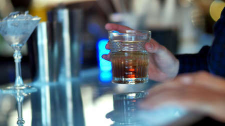 Hand holding a glass of whiskey in barの写真素材