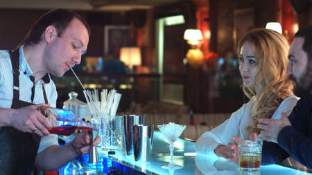 Bartender pouring mixed cocktail for clients in a barの写真素材