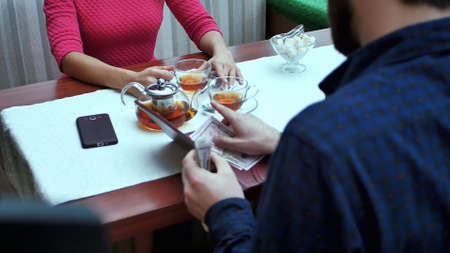 Happy couple with wallet paying bill at restaurant with dollar cash