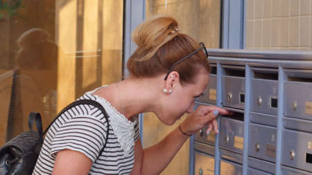 Pretty young woman checking her mailbox for new lettersの写真素材