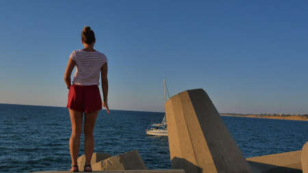 Beautiful fit girl in shorts dancing on big rocks near the seashoreの写真素材
