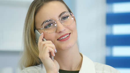 Female nurse at hospital reception talking on the phone