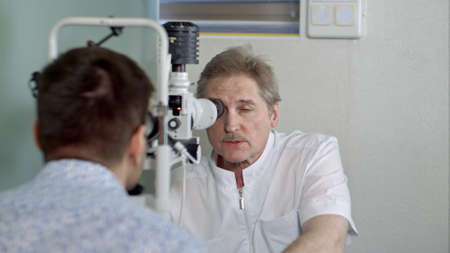 Ophthalmologist and young man checking eyesight in clinicの写真素材