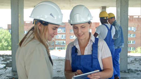 Construction worker and engineer working on building site, using digital tabletの写真素材