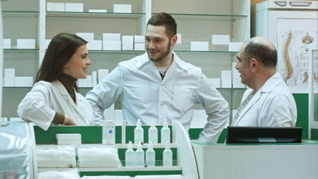 Team of pharmacist chemist woman and man standing in pharmacy drugstore and talking positive