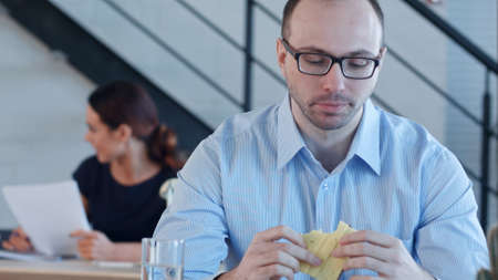 Young business man sitting and eating sandwich with cheese in officeの写真素材