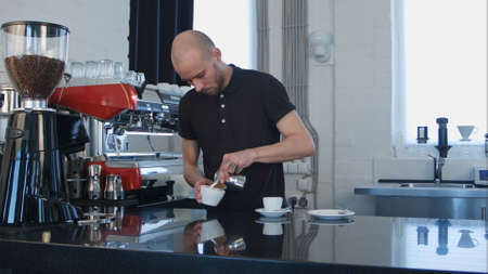 Barista pouring coffee into white cupの写真素材
