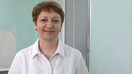 Portrait of aged female doctor on hospital corridor looking at camera smilingの写真素材