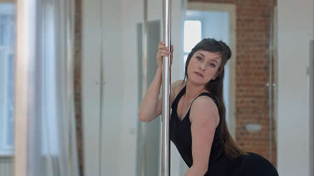 Young pole dancer woman wearing balck sports wear training and looking at cameraの写真素材