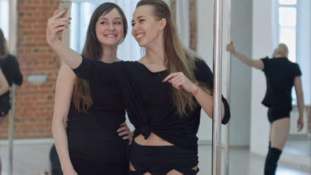 Beautiful young women taking a selfie during a break on a pole fitness classの写真素材