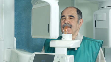 Senior patient doing examination of teeth by using panoramic and cephalometric X-Ray scannerの写真素材