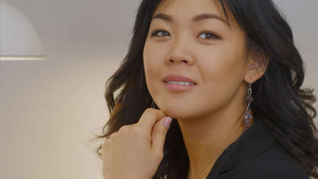 Pretty asian woman looking through the window with a smileの写真素材