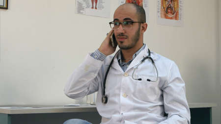 Smiling male doctor having a cheerful phone conversationの写真素材