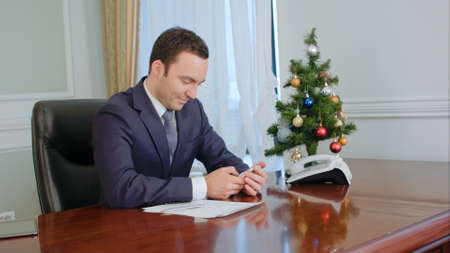 Buisnessman congratulates colleagues, texting SMS using a mobile phone and smilingの写真素材