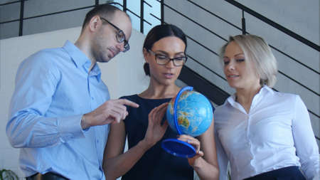 Three teachers discuss something with globeの写真素材
