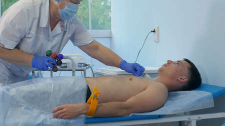 Nurse performing electrocardiography on a male patientの写真素材