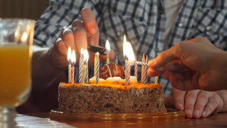 Two hand lighting candles in birthday cakeの写真素材