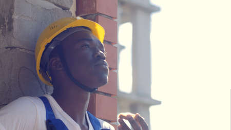 Construction afro-american worker take a break eating a sandwich