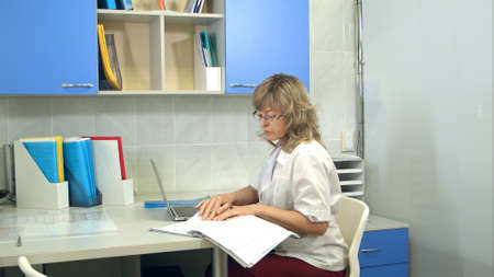 Female doctor using laptop sitting at desk in her officeの写真素材