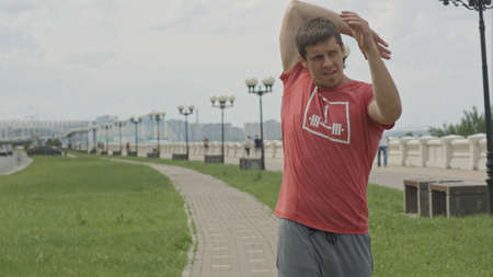 Handsome athlete warming up before jogging outdoors