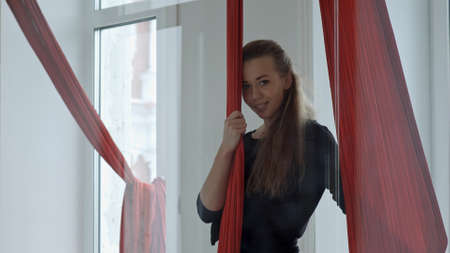Young female pole dancer standing near to a aerial fabric and looking at camera, smilingの写真素材