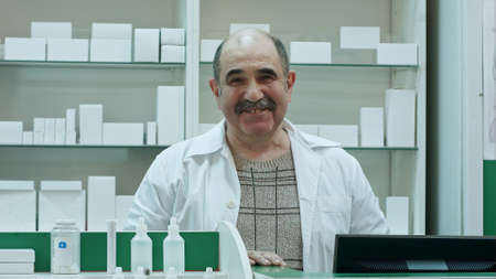Portrait of senior pharmacist smiling and talking to a cameraの写真素材