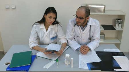 Pretty young nurse showing something on digital tablet to her male colleagueの写真素材