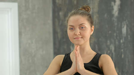 Ypung blonde woman namaste practicing yoga in a studio indoorsの写真素材