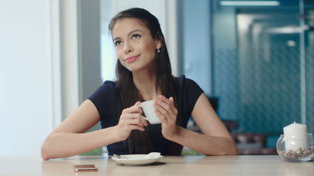 Pretty young woman sitting in a cafe with a cup of coffeeの写真素材