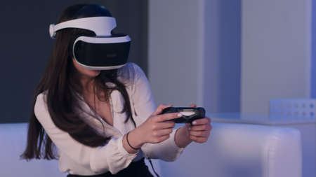 Woman wearing virtual reality device and playing video game with gamepadの写真素材