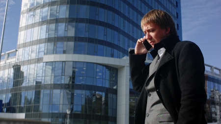 Happy businessman using cell phone outside officeの写真素材
