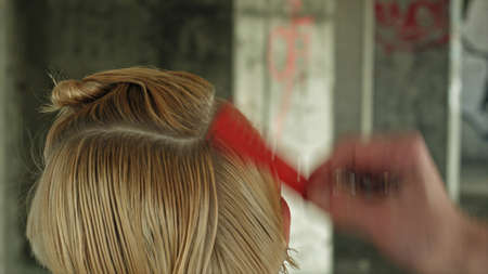 Young fashion woman hairdresser makes hairstyle for a girl.の写真素材