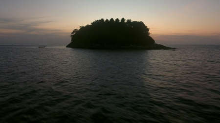 Low flying over fishing boat near wild island with sunset viewの写真素材