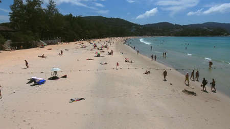 Aerial view of crowd of tourists get rest on sea beach near little village at summer sunny dayの写真素材