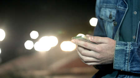 A man send message by smartphone at city nightの写真素材
